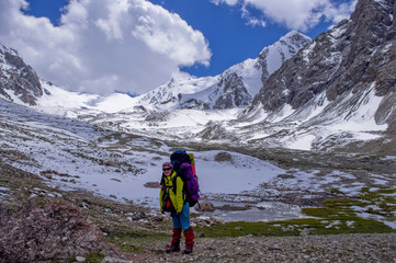 Fototapeta premium girl on the background of mountain scenery. girl standing with a backpack with equipment on the background of the glaciers.