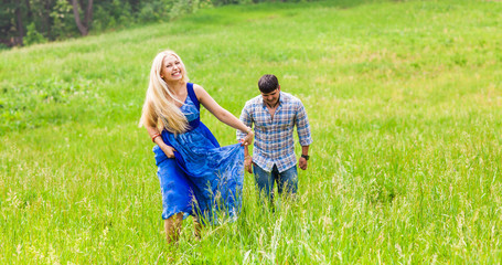 Happy couple running on a meadow in summer nature
