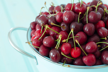 colador turquesa con cerezas