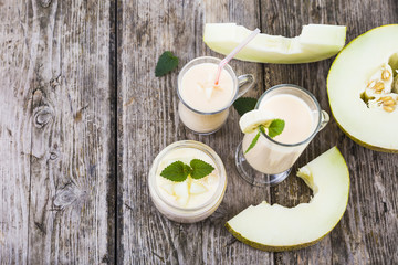 Yogurt and smoothie with melon on a wooden table.