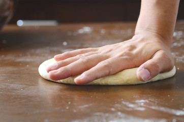 Bread cooking,kneading bread dough on wooden board by hand
