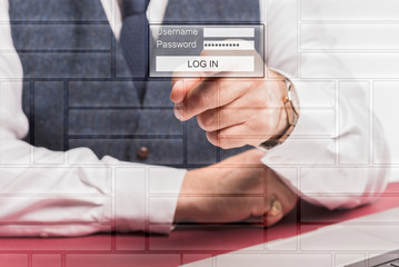 Business man sitting at desk infront of computer pressing a virtual log in button on the screen.