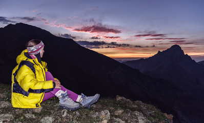 girl climber sitting on a rock and looking at the beautiful sunset in the mountains of Kyrgyzstan.