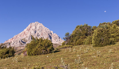mountain landscape, a clear day, the sky on the moon. around the mountains, trees, greenery
