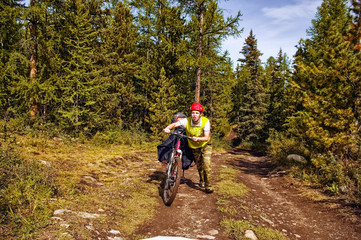 Altai mountain road. The photo was taken during a cycling trip through the Altai in the summer in August. Russia. Cyclist goes with the bike. A man on a bicycle.