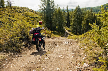 Altai mountain road. The photo was taken during a cycling trip through the Altai in the summer in August. Russia. Cyclist goes with the bike. A man on a bicycle.