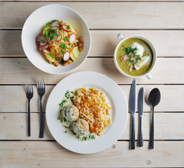 Table served for dinner. Salad with radish and cabbage, soup-puree with meat and meatballs with rice.