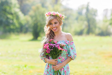 outdoor portrait of a beautiful blonde woman. attractive happy girl in a field with bouquet of flowers.