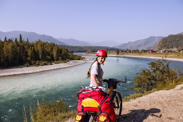Russia, the Republic of Altai. Biking in Beluha area. Young woman girl standing with a bicycle. Portrait. Sports hiking. Around the mountains, greenery, blue sky, river Katun.