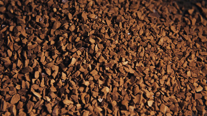 Instant coffee granules scattered brown closeup.
