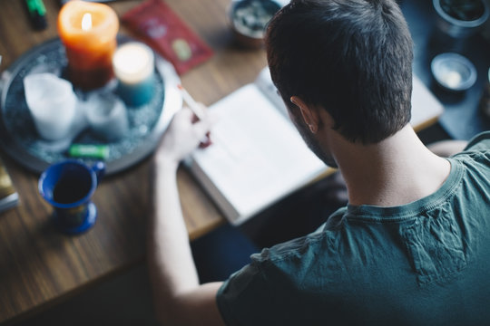 Rear view of man studying at table in college dorm room