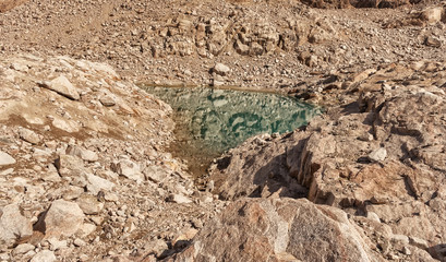 mountain lake among stones. sunny. turquoise water. rock