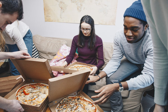 Friends opening pizza boxes in college dormitory