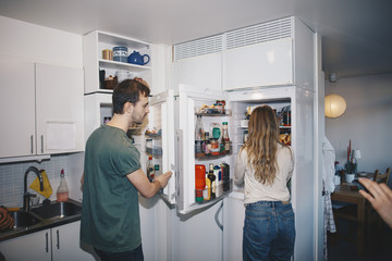 Man and woman standing by refrigerators in kitchen at college dorm