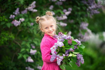 Portrait of beautiful cheerful girl with a bouquet of lilacs in summer park