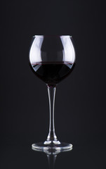 Pouring red wine into the glass against wooden background