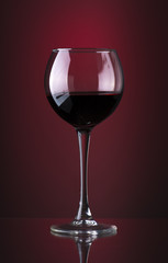 Pouring red wine into the glass against wooden background