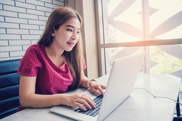 Asian girl working at a coffee shop with a laptop.female freelancer connecting to internet