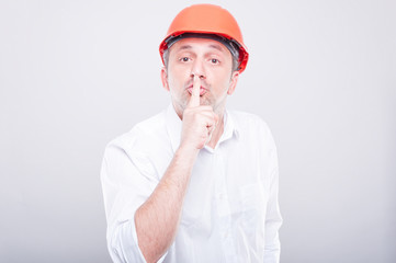 Portrait of contractor wearing hardhat making sush gesture