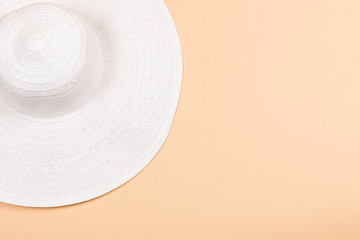 Fototapeta na wymiar White female hat with seashells on a beige background