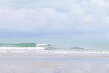 Nature background concept : Sand beach and clear transparent sea wave with foam and blue sky