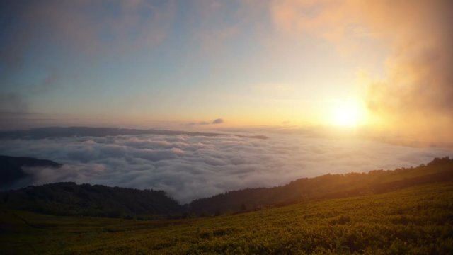Brilliant summit dawn above flowing cloud waves, red sun disk time lapse
