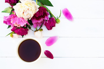 Peonies and a cup of coffee on a white wooden table