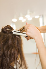 Naklejka premium beauty and people concept - happy young woman with hairdresser at hair salon.