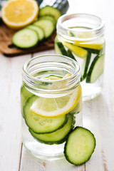 Detox water with cucumber and lemon on white wooden table
