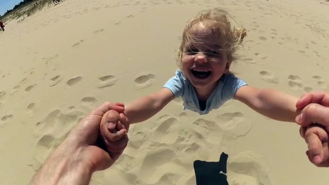 Parent Spinning Daughter By Hands On Beach Slow Motion POV