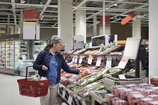 Mature woman buying at vegetables on display in supermarket