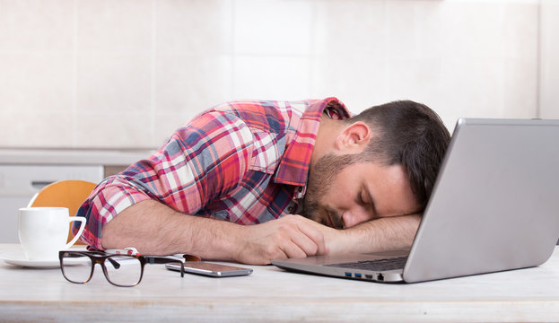 Man sleeping above laptop at home