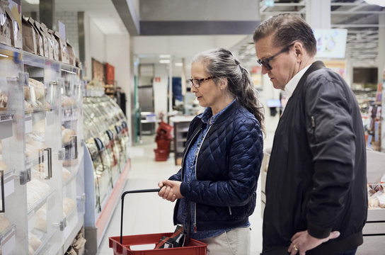 Mature couple looking at food cabinet in supermarket
