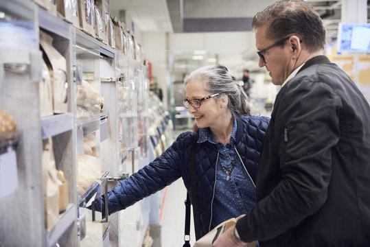 Smiling woman taking food from cabinet while standing with man at supermarket