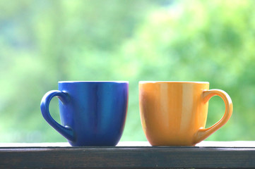 A beautiful cup with hot tea stands in front of a beautiful scenery