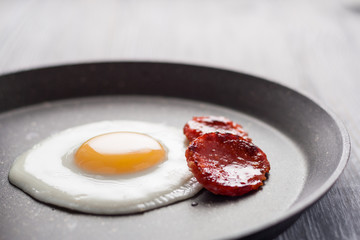 Breakfast on the table. Fried eggs with fried sausages salami and dill.