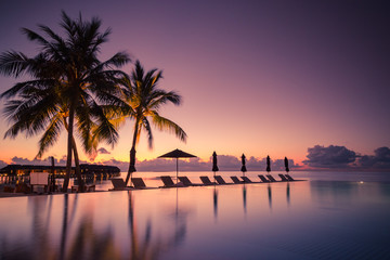 Fototapeta na wymiar Luxury poolside on the beach with sunset colors. Amazing luxury summer background