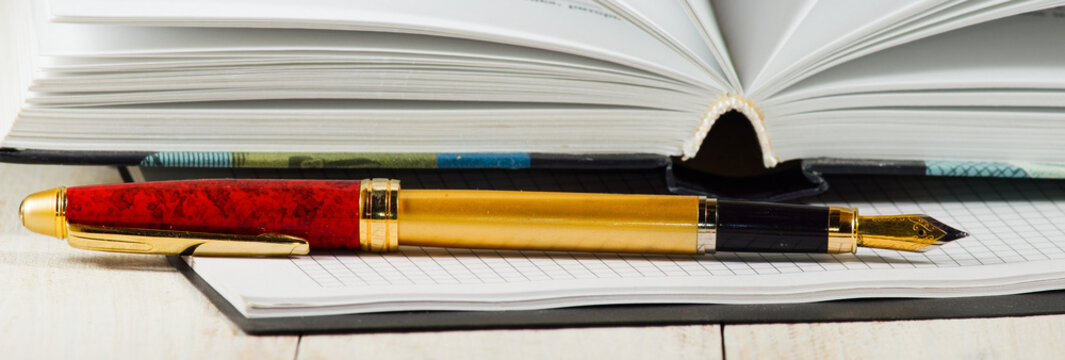 Image of pen, notebook and book close-up