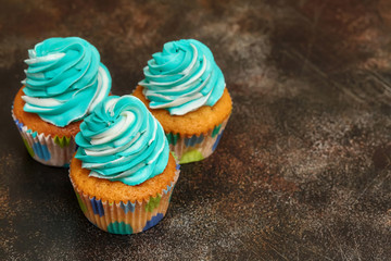 Cupcakes with turquoise and white buttercream frosting on brown background