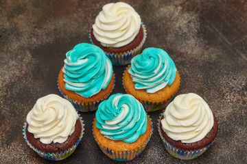 Cupcakes with turquoise and white buttercream frosting on brown background