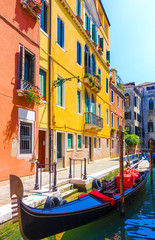 Fototapeta na wymiar Picturesque view of gondola moored on peaceful narrow canal in front of colorful buildings in Venice, Italy