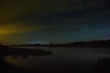 Bright stars in the night sky with clouds on a background of the river.