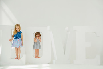 Two girls girlfriends stand on the huge letters that make up the word love. Play with Love