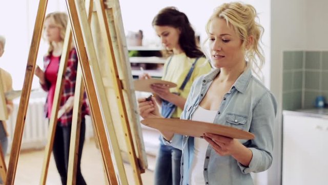 students with easels painting at art school