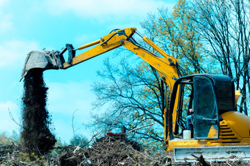 Digger or excavator machine with yellow shovel