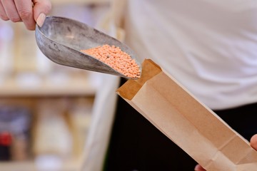 Woman pouring red lentil into paper bag