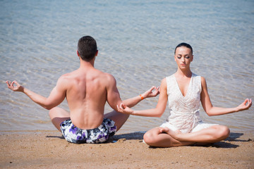 couple of muscular man and woman meditating, yoga pose, love