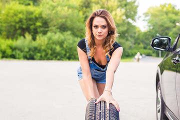 Sexy woman changing wheel on a roadside