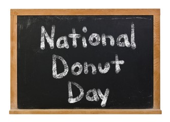 Fototapeta premium National Donut Day written in white chalk on a black chalkboard isolated on white