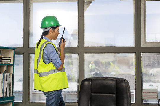 Female quarry worker standing in site office talking on radio device